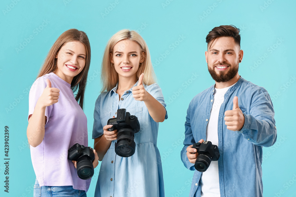 Poster Group of young photographers showing thumb-up gesture on color background