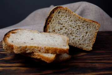 Half a loaf and sliced pieces of bread on a wooden board. Sourdough bread.