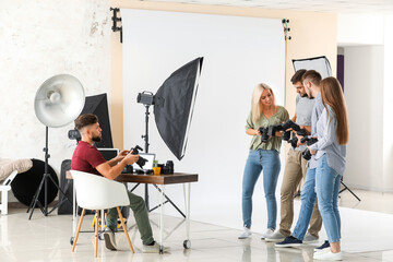Group of young photographers in studio - obrazy, fototapety, plakaty