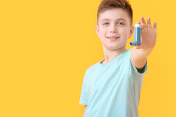 Little boy with inhaler on color background