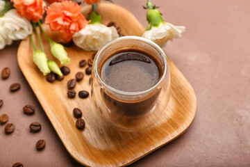 Cup of coffee with spring flowers on color background