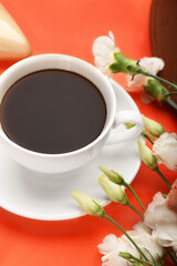 Cup of coffee with spring flowers on color background