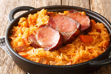 Sauerkraut baked with onions, bacon, carrots and smoked pork in a skillet on the table. horizontal