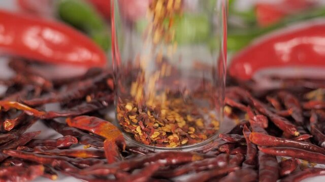 Flakes of red pepper falling inside a transparent bottle - spices and seasoning. Dried hot whole chilies (lal mirch) with its flakes - spicy food with Indian masala 