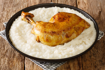 Delicious rice cooked in broth with milk and butter, and chicken quarters close-up on a plate on the table. horizontal