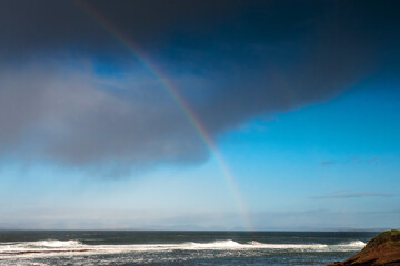 Colorful rainbow over Atlantic ocean, Mullaghmore, county Sligo, Ireland. Blue cloudy sky.