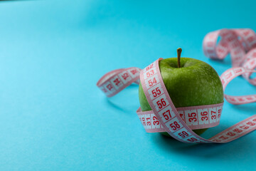 Green apple with measuring tape on blue background