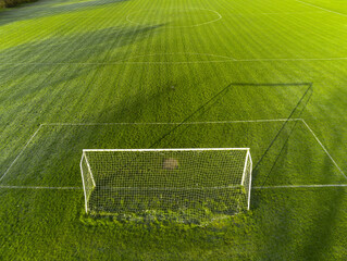 Aerial view on a green grass football or soccer field . Long shadows on the ground. Nobody....