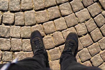legs in black sneakers on the pavement