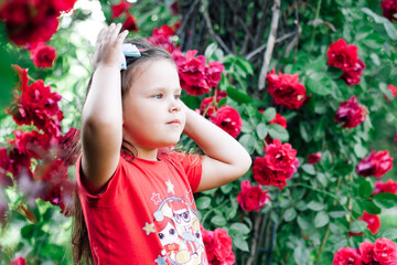 close-up portrait in profile of a beautiful, charming girl looking into the distance with a background of an arch of roses.