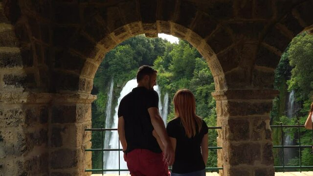 Couple of man and woman look at water discharge, strong flow. The Cascata delle Marmore is a the largest man-made waterfall. Terni in Umbria Italy. Vacation concept. View point.