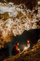 Speleologists wondering and admiring stalactites in a cave