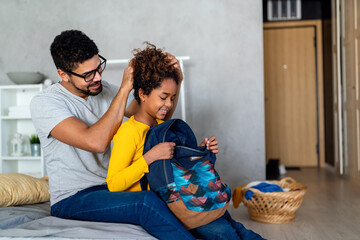 Obraz premium Black father helping daughter pack her bag for school