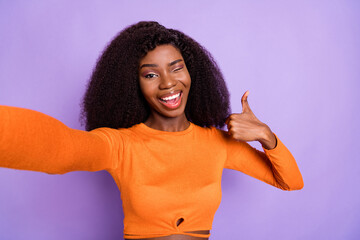 Photo of funky sweet dark skin lady wear orange shirt record video winking showing thumb up...