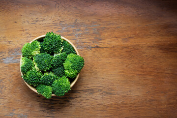Fresh cut broccoli in wooden bowl on rustic wooden background - 423910557