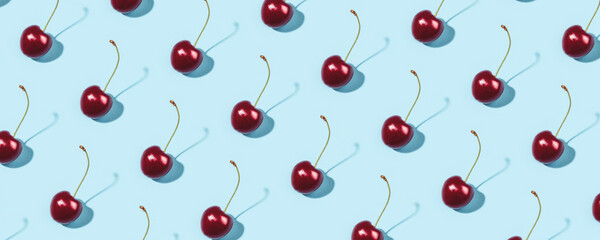 Bright pattern of ripe cherries on a blue background. Flat lay, top view.