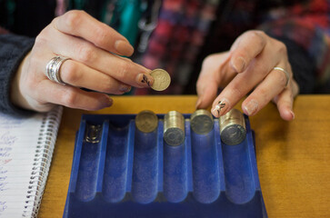 A woman counting coins in a shop, close up hands and coins