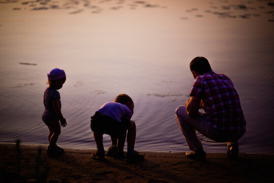 family, children and parents , rocky river bank at sunset