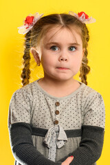 Beautiful little girl on a yellow background in meditation dreams of the future.