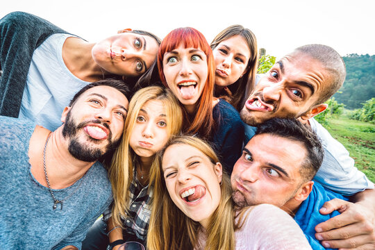 Best friends taking funny selfie at picnic excursion sticking out tongue - Youth life style concept with young people having fun together outdoors - Warm bright filter with focus on central faces