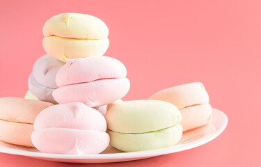 Fruit marshmallows on a plate as breakfast. Natural colored marshmallows on a pink background. Selective focus.