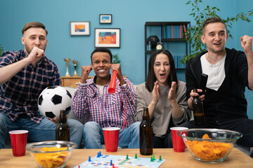 Diverse mix of friends watching sport on tv together at home screaming cheerful. Group of friends sitting on the couch and watching a football game.