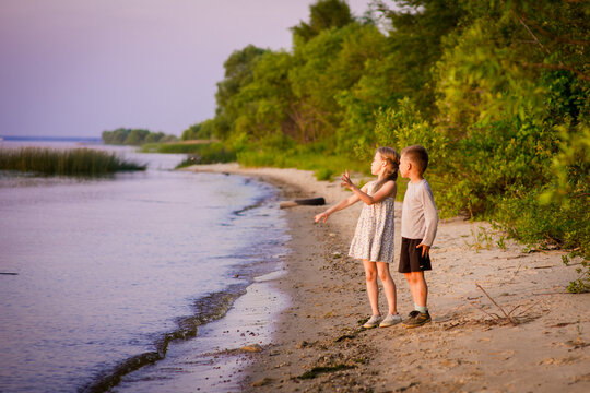 a girl with her little brother on a rocky riverbank