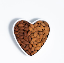 Roasted almond in heart shape bowl on white background - 423915130