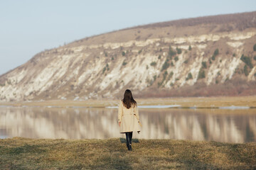 Stylish woman traveler walking on background of river in mountains. Travel and wanderlust. 