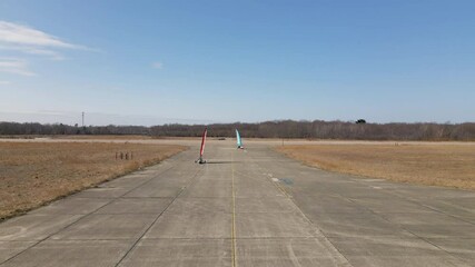 Two land sailing yachts turning corner and heading towards camera at South Weymouth Naval Air Station - decommissioned naval base.  Static shot