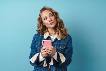Blonde thinking woman using mobile phone and looking aside