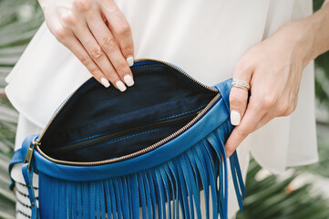 Women's bag blue with fringe inside view. Women's hands show the interior departments of a women's...