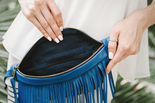 Women's bag blue with fringe inside view. Women's hands show the interior departments of a women's bag.