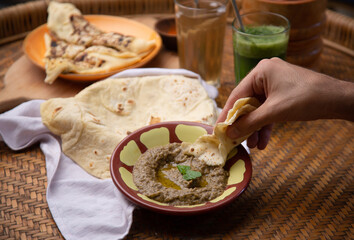 Close up of hands taking Middle eastern or arabic dishes and assorted meze: hummus, pita, Manakish Lahm Bi Ajeen - Flatbreads topped with minced meat and Fatayer stuffed pie. Delicious Halal food