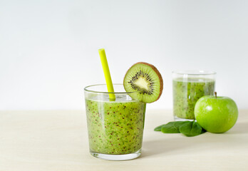 kiwi, apple and spinach smoothies. green smoothie in a glass with kiwi and straw