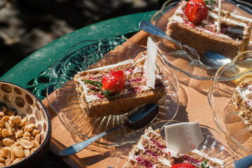 Pieces of sweet cake on glass plates on metal garden table