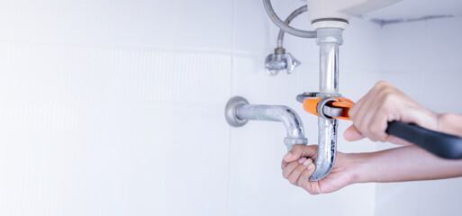 Plumber working in the bathroom, plumbing repair service, repairing leaking sinks with adjustable...