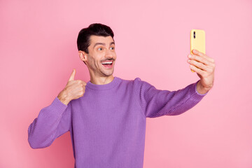Photo of funny charming man dressed purple pullover showing thumb up tacking selfie modern device isolated pink color background