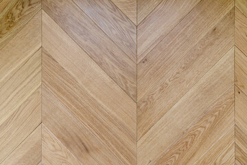 Top view of an french herringbone parquet floor under natural light. Wooden pattern with oak diagonal texture.