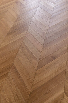 Top view of an french herringbone parquet floor under natural light. Wooden pattern with oak diagonal texture.