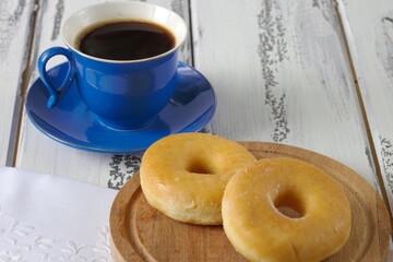 Delicious donuts are next to a Cup of coffee, poured into a blue Cup.