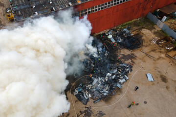 Aerial view of firefighters extinguishing fire in industrial area.