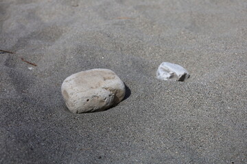Fototapeta na wymiar Grauer Sand mit zwei Steinen