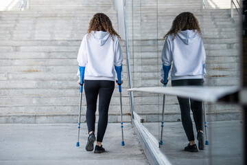 Girl from back with crutches, walking alone