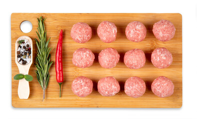 Raw meat balls on a chopping board. Chili pepper, rosemary, spices.