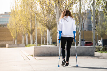 Girl from back with crutches, walking alone