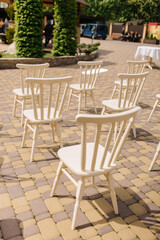 Fototapeta na wymiar White wooden chairs stand in the yard. Chairs for a wedding ceremony