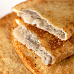 Puff pastry pie stuffed with meat filling. Fresh cheburek, fried bread with meat. Delicious snack or nutritious lunch on the run. Takeaway food concept. Square format. Soft focus.
