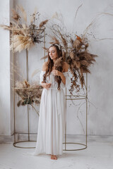  Girls in a white boho dress sweet posing against the background of dried flowers