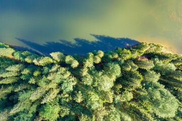 Top down aerial view of big lake with clear blue water between high mountain hills covered with...